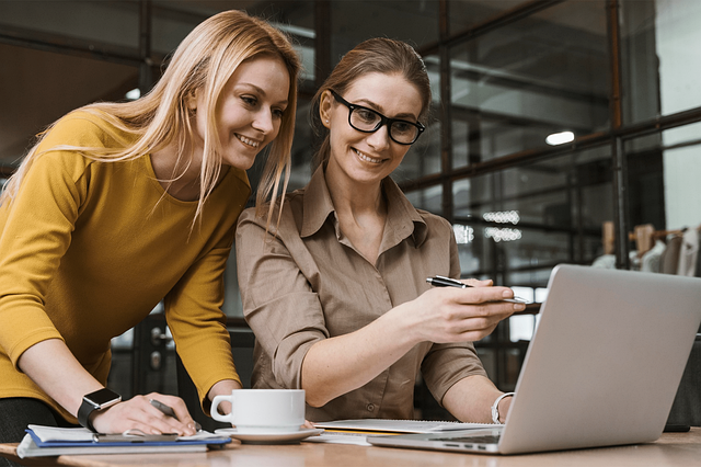 Personalized Marketing Two professional women are looking at a laptop, aligning content with customers to enhance personalized content marketing ROI.